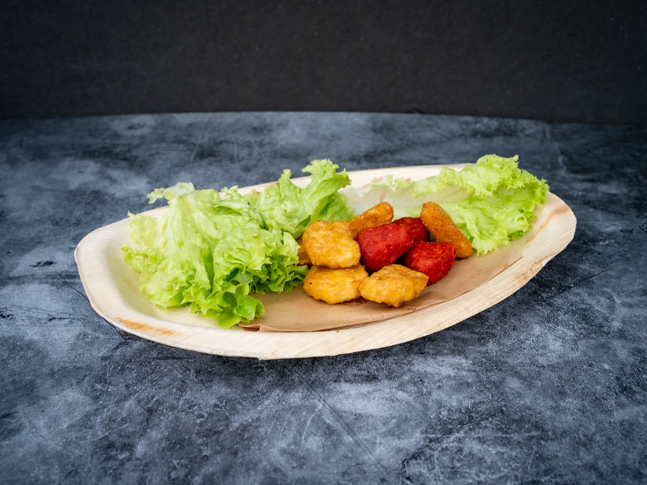 Close-up of crispy golden nuggets with fresh lettuce served on a rustic wooden plate.